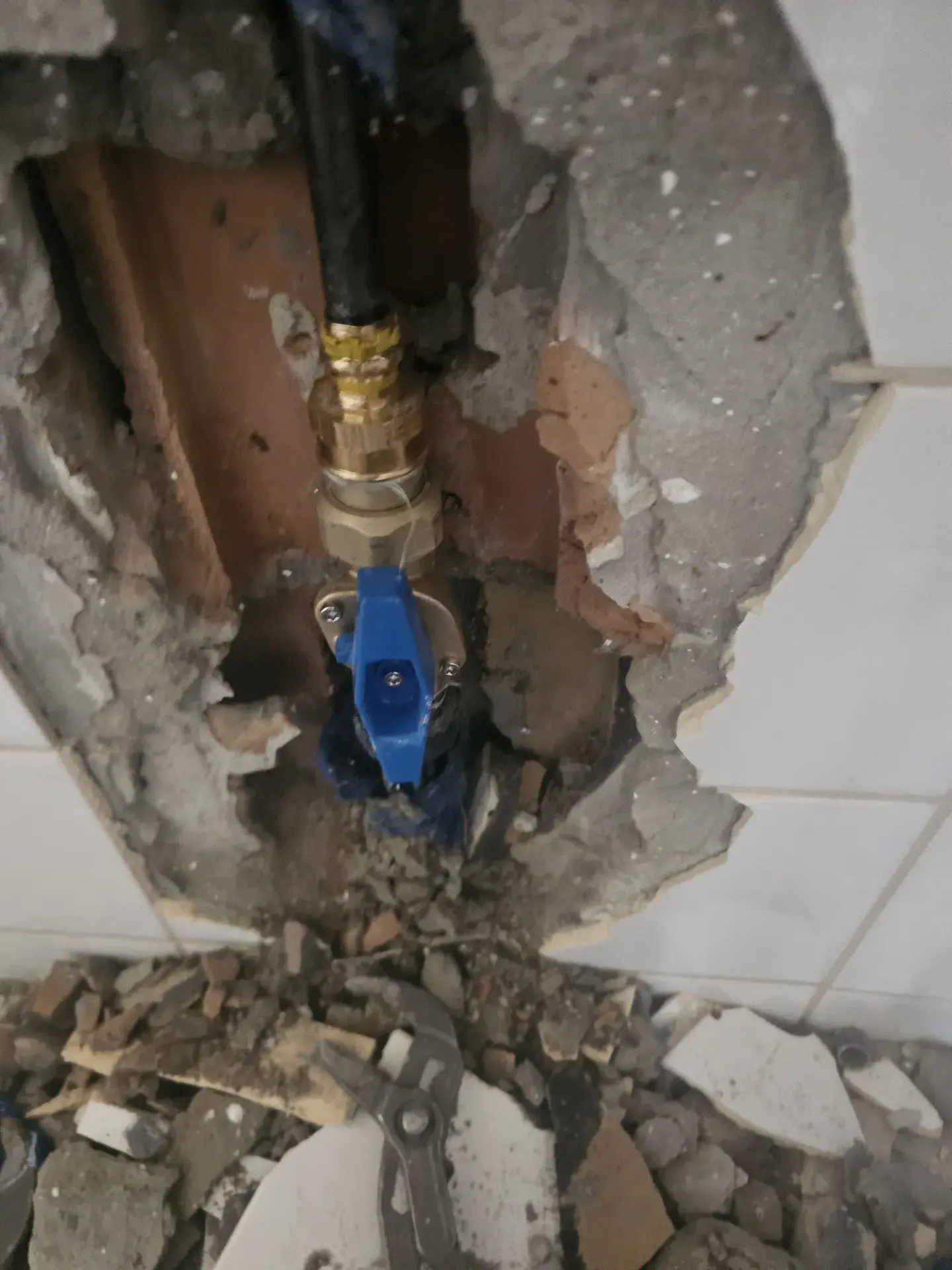 A képen az Ösküben található HydroArt Kft. Épületgépészet cég által végzett munkálatok láthatók. Az épület falán egy nagyobb méretű lyuk van, amely mögött vízvezeték-szerelvények és csövek láthatók. A falon látható törmelék, amely a felújítás során keletkezett, és a környezetében szerszámok is találhatók.